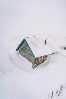 couvert de neige en bois chalet sur une Montagne pente. Haut vue photo