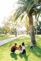 Parents avec une peu fille accroupi dans le parc dans de face de une petit fille photo