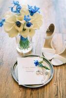 mariage anneaux mensonge sur une rond plateau suivant à le invitation près une mariage bouquet de fleurs dans une vase photo