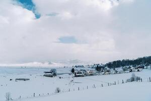 couvert de neige village à le bord de le forêt dans une Montagne vallée photo