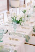 longue de fête table avec bouquets de fleurs et transparent assiettes photo