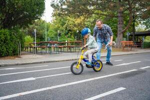 content famille père enseigne enfant fille à balade Publique bicyclette sur un de circulation terrain de jeux de Prague, tchèque république, L'Europe . haute qualité photo