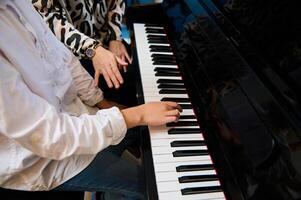 sélectif concentrer à adolescent garçon musicien pianiste les doigts et piano clé à jouer le piano. fermer enfant en jouant le piano pendant individuel la musique leçon en dessous de le sien enseignants orientation photo