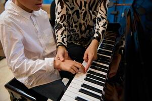 fermer coup de une la musique professeur, femelle pianiste expliquant correct mains et doigt position sur piano clés, enseignement piano cours à maison. créer la musique et Chansons concept. loisir et loisir à l'intérieur. photo