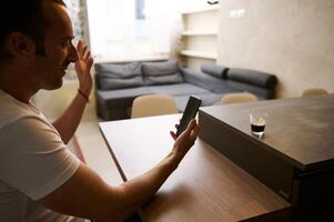 souriant homme d'affaire séance à bureau, ayant vidéo appel sur intelligent mobile téléphone dans le Bureau ou à maison. photo