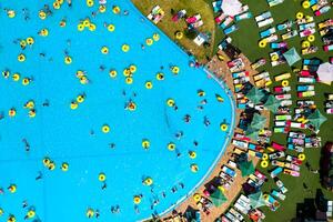 Haut vue de gens relaxant dans le bassin sur Jaune gonflable cercles et Soleil des lits sur le plage photo