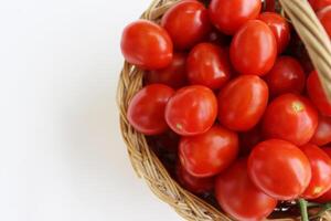 beaucoup rouge Cerise tomates avec sépales dans le panier isolé sur le blanc Contexte. tomate pile. mûr et Frais biologique des légumes récolté de local Les agriculteurs. coupure chemin. Haut voir. copie espace. photo