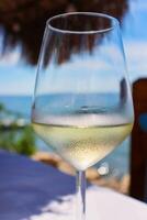 verre de un la glace du froid vigne sur le table dans le 2 Kitarrat arome déti restaurant sur le adriatique plage dans Durrès, Albanie. magnifique ensoleillé été journée. bleu ciel et le mer. sélectif concentrer photo