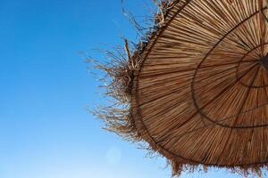 Albanie. durrès. fermer de le paille Soleil parapluie sur le adriatique plage. une magnifique ensoleillé journée et le bleu ciel sur le Contexte. paille texture. copie espace. sélectif se concentrer. photo