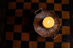 allumé bougie sur le en bois échiquier. brûlant bougie sur le en bois table dans le bougeoir. brûlant lumière. confortable atmosphère. copie espace. contre-jour de le la fenêtre. Haut voir. sélectif se concentrer. photo