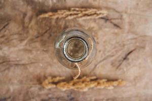 nature morte d'un bouquet de fleurs séchées dans une bouteille en verre sur une table en bois. place pour le texte ou la publicité. vue d'en-haut photo