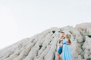 Fille blonde dans une robe bleu clair et un gars dans une chemise légère dans une carrière de granit photo