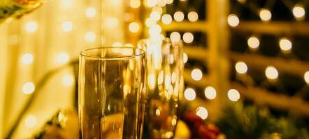 deux Champagne des lunettes rempli avec Champagne sont mis sur une table avec une fruit arrangement. le des lunettes sont entouré par lumières, création une de fête atmosphère. photo