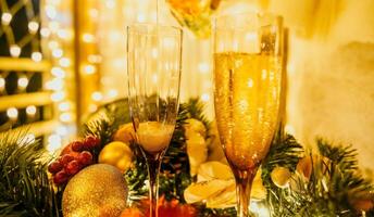 deux Champagne des lunettes rempli avec Champagne sont mis sur une table avec une fruit arrangement. le des lunettes sont entouré par lumières, création une de fête atmosphère. photo