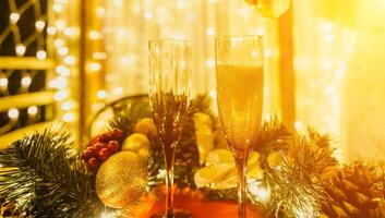 deux Champagne des lunettes rempli avec Champagne sont mis sur une table avec une fruit arrangement. le des lunettes sont entouré par lumières, création une de fête atmosphère. photo