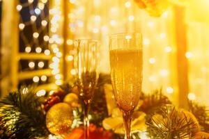 deux Champagne des lunettes rempli avec Champagne sont mis sur une table avec une fruit arrangement. le des lunettes sont entouré par lumières, création une de fête atmosphère. photo