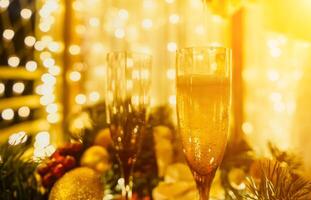 deux Champagne des lunettes rempli avec Champagne sont mis sur une table avec une fruit arrangement. le des lunettes sont entouré par lumières, création une de fête atmosphère. photo