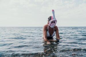 Jeune content femme dans blanc bikini et portant rose masque obtient prêt pour mer plongée en apnée. positif souriant femme relaxant et profiter l'eau Activités avec famille été Voyage vacances vacances sur mer. photo