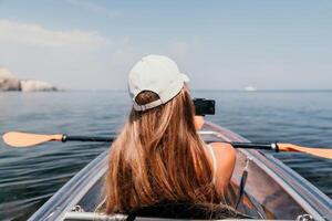 femme dans kayak retour voir. content Jeune femme avec longue cheveux flottant dans transparent kayak sur le cristal clair mer. été vacances vacances et de bonne humeur femelle gens relaxant ayant amusement sur le bateau photo