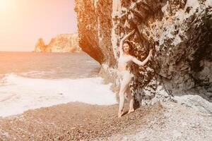 femme Voyage mer. sportif content milieu vieilli posant sur une plage près le mer sur Contexte de volcanique rochers, comme dans Islande, partage Voyage aventure périple photo