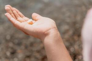 femme en mangeant laiteux amande des noisettes. une Jeune caucasien femme couper Frais vert amande après Matin aptitude yoga près mer. seulement mains sont visiblement. en bonne santé végétalien aliments. lent mouvement. proche en haut photo