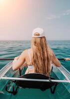 femme dans kayak retour voir. content Jeune femme avec longue cheveux flottant dans transparent kayak sur le cristal clair mer. été vacances vacances et de bonne humeur femelle gens relaxant ayant amusement sur le bateau photo
