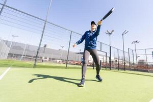 une fille dans tenue de sport est formation sur une pagayer tennis rechercher. le fille est frappe le Balle contre le verre à faire une rebond. concept de femmes en jouant pagayer. photo