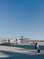 Podgorica, Monténégro - 16 août 2023. les passagers avec les valises marcher le long de le piste à planche le avion photo