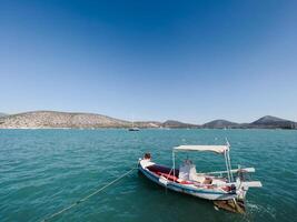 afines, Grèce - 20 août 2023. petit bateau avec rames est amarré près le mer contre le toile de fond de une Montagne intervalle photo