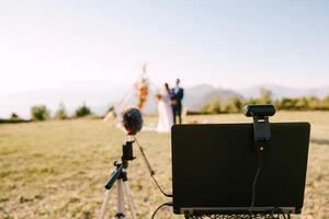 portable avec une webcam et une microphone des stands contre le Contexte de le la mariée et jeune marié près le mariage cambre photo