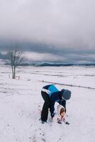 papa penché plus de le peu fille mensonge sur sa estomac dans le neige et levé sa photo