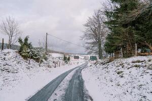 Autoroute par neigeux forêt à village avec coloré Maisons dans Montagne vallée photo