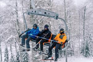 touristes dans ski costume et des skis balade sur une ski ascenseur en haut une couvert de neige Montagne au dessus le forêt photo