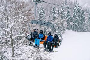 skieurs dans casques et ski costume balade en haut le pente au dessus le neigeux forêt photo