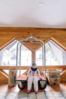 peu fille dans une ski costume est assis sur une Hôtel bagage Chariot dans le hall photo