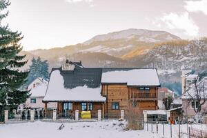 à deux étages en bois chalet dans une neigeux village à le pied de le montagnes photo