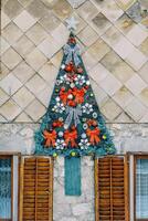 se sentait Noël arbre avec rouge arcs et guirlandes bloque sur le mur de le maison photo