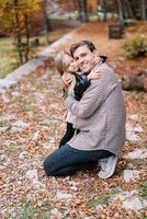 souriant papa étreindre peu fille tandis que a genou dans l'automne parc photo