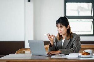 multitâche femme d'affaires est sur une téléphone appel, avec sa portable ouvert dans une détendu café espace de travail. photo