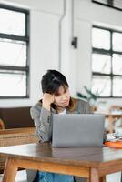 Jeune professionnel apparaît frustré et fatigué tandis que travail sur sa portable dans une brillant espace de travail. photo