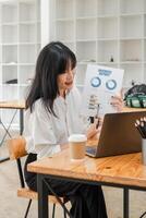 asiatique femme d'affaires avec un appareil dentaire avec enthousiasme discuter une financier rapport pendant une vidéo appel dans une minimaliste bureau. photo