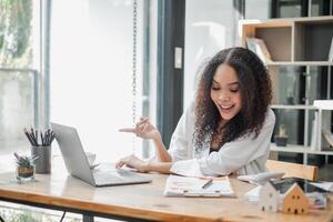 réel biens agent avec une amical comportement est activement engagé à sa ordinateur portable, organiser propriété Ventes dans une bien éclairé, moderne espace de travail. photo