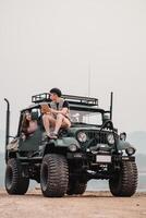 Jeune couple est Profond dans discussion plus de une carnet de notes, confortablement assise un haut leur modifié voiture, ensemble contre une brumeux Montagne paysage. photo