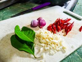 tranché piments, tranché oignons et baie feuilles sur une Coupe planche comme cuisine épices pour traditionnel indonésien nourriture photo