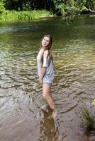 adolescent caucasien femme Extérieur permanent dans rivière portant gris robe photo