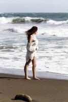 latina femme permanent sur le sable plage avec océan vagues photo