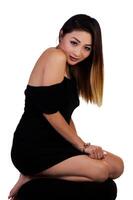attrayant asiatique américain femme a genou dans noir robe sur blanc photo