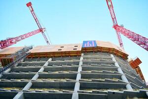 haute monter bâtiment en dessous de construction. installation de verre façade panneaux sur une renforcé béton structure. photo