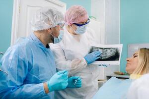 dentiste expliquant le détails de le radiographie à le sien patient dans le Bureau photo