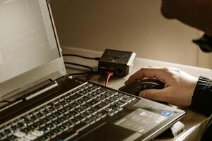 proche en haut de homme main en utilisant sans fil Souris et portable ordinateur avec bleu rétro-éclairé clavier photo